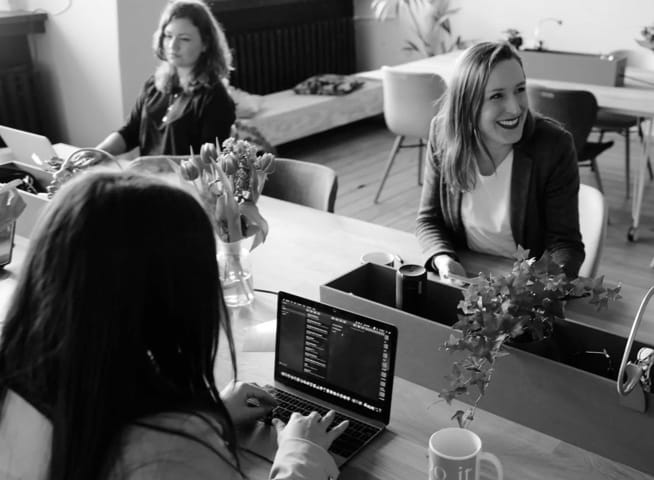 Three people working with their computer at an office table.